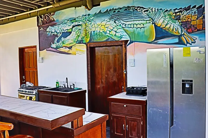 A kitchen with an alligator painted on the wall.