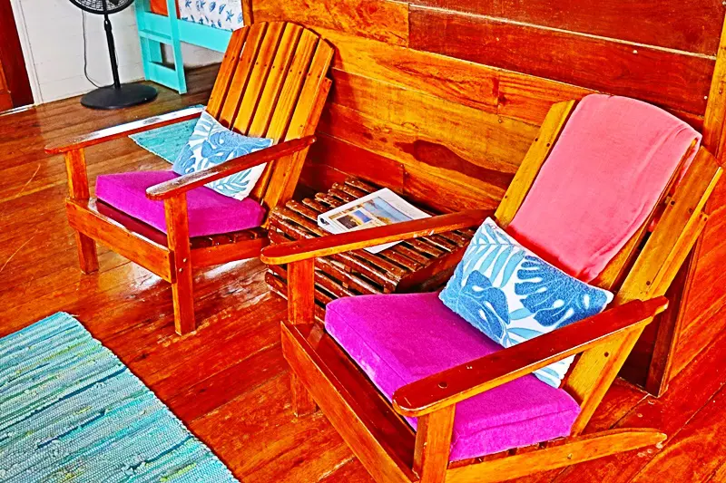 Two wooden chairs with pillows on them.