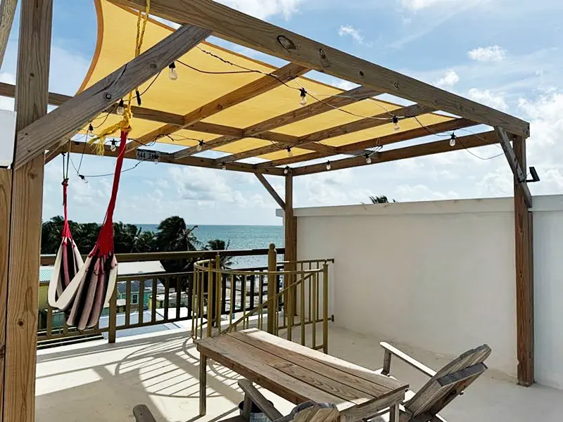 A wooden table and chairs on the patio of an ocean front home.