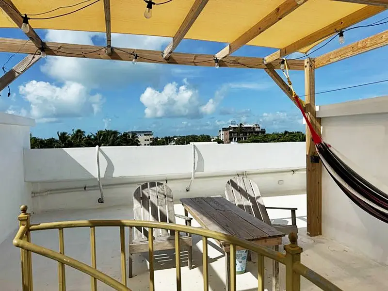 A patio with chairs and tables under an umbrella.