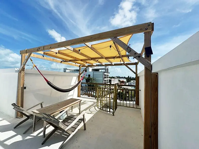 A hammock is hanging over the roof of a patio.