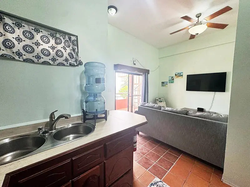 A kitchen with sink and tv in the room