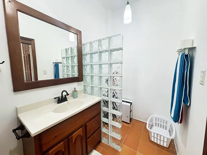 A bathroom with a sink, mirror and shower.