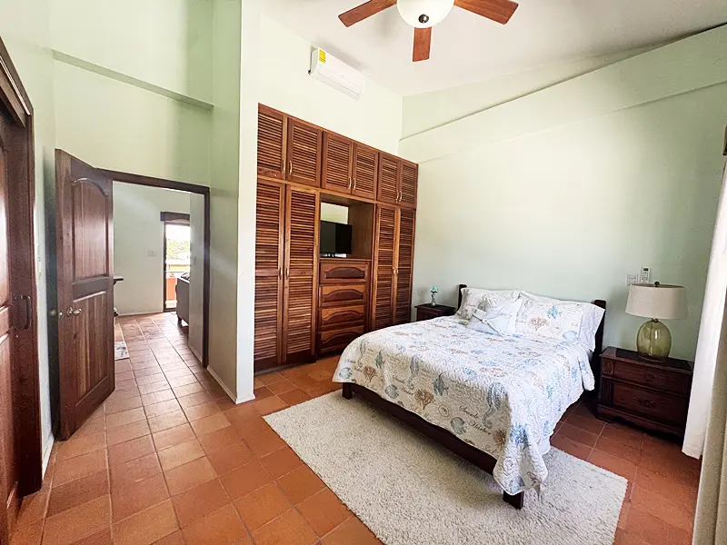 A bedroom with a bed, dresser and closet.