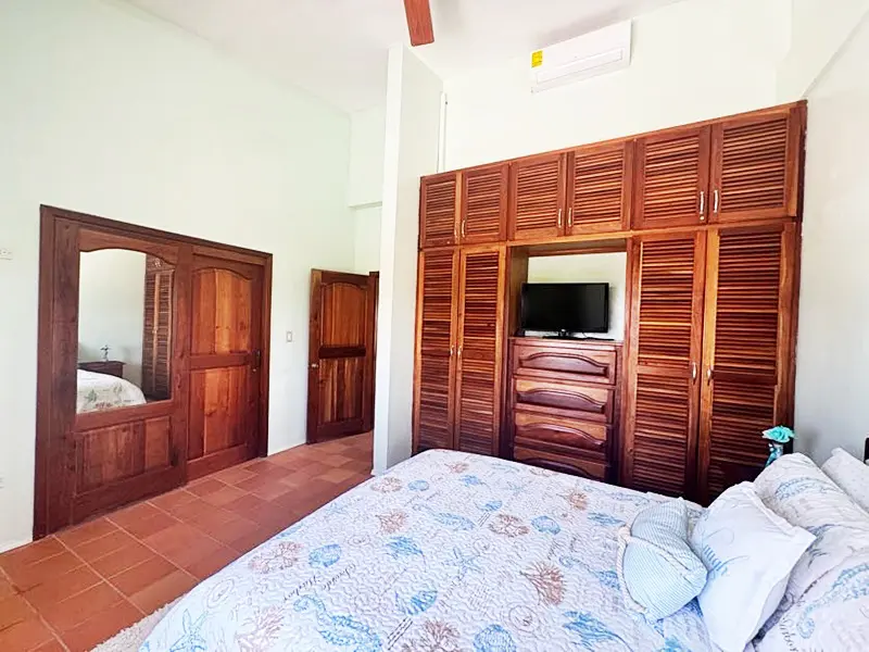 A bedroom with a bed, dresser and mirror.