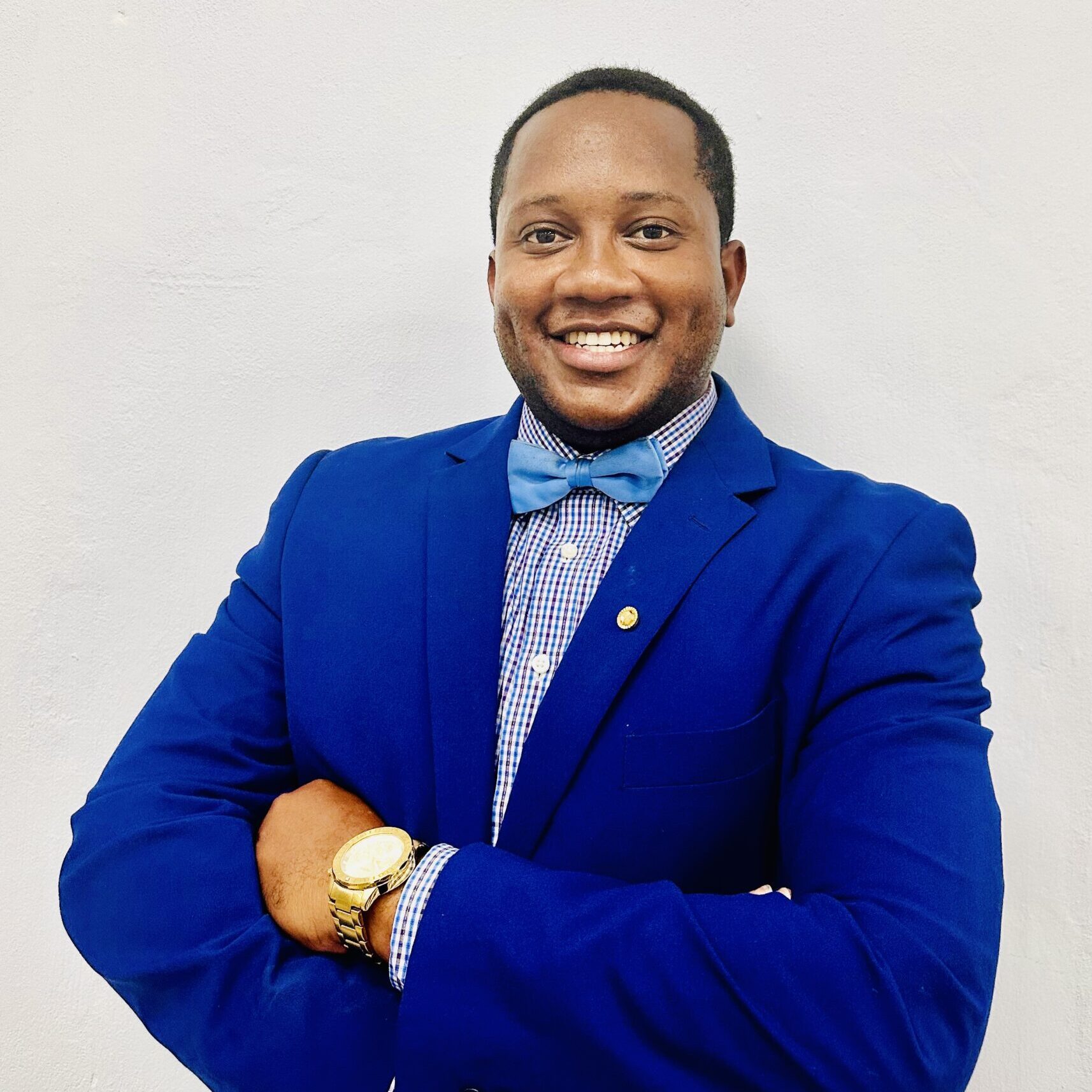 A man in blue jacket and bow tie standing with his arms crossed.